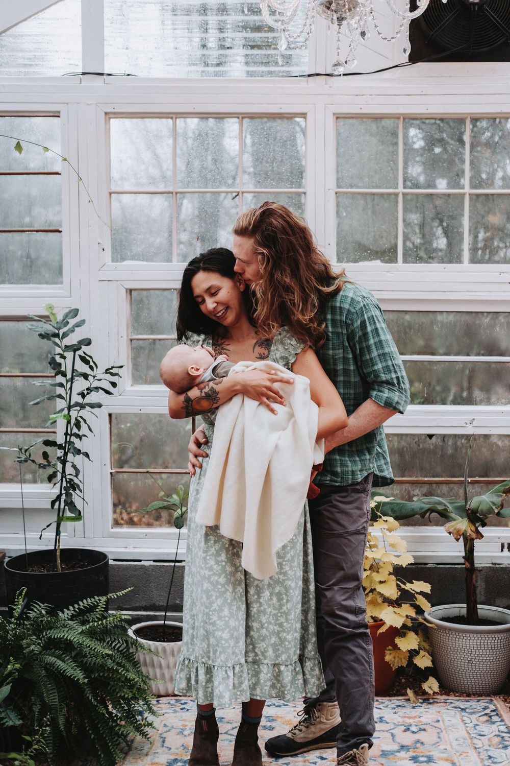 Tender moment shared in a greenhouse filled with plants and natural light.