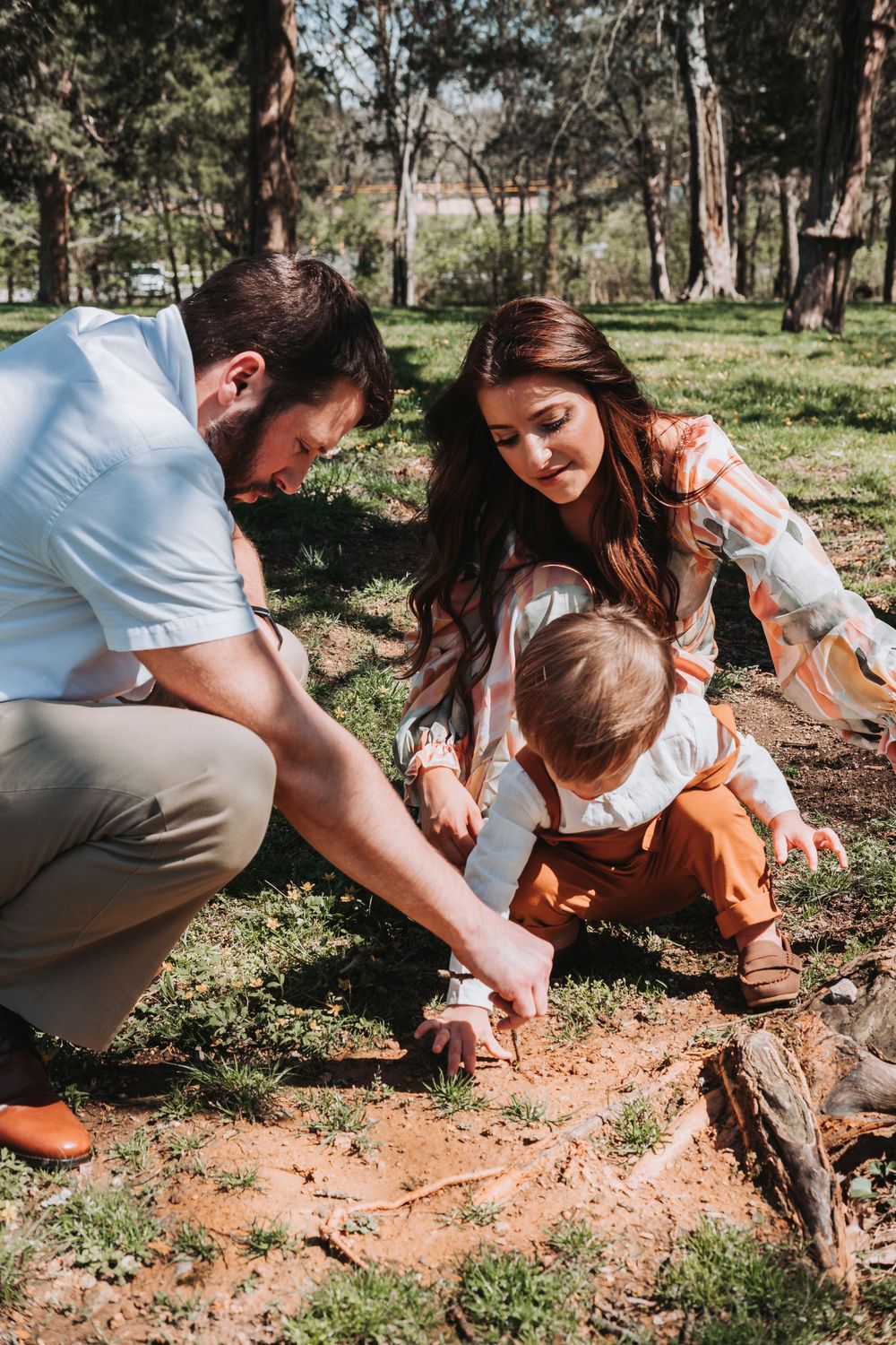 Family explores nature together in a wooded park setting.