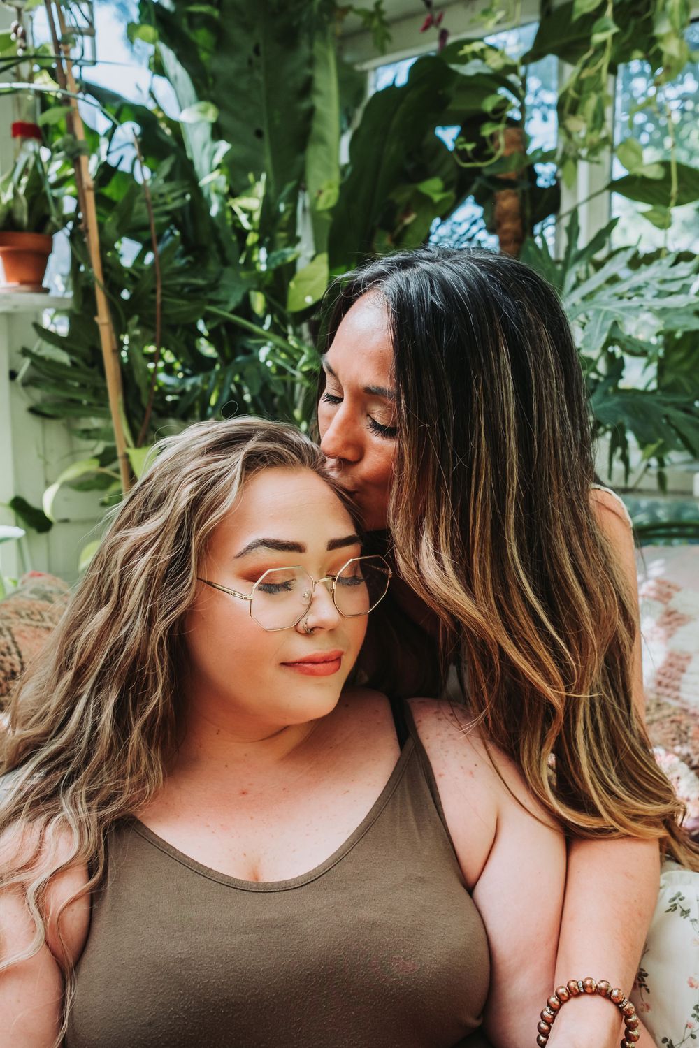 An intimate close-up portrait of two people embracing among green plants.