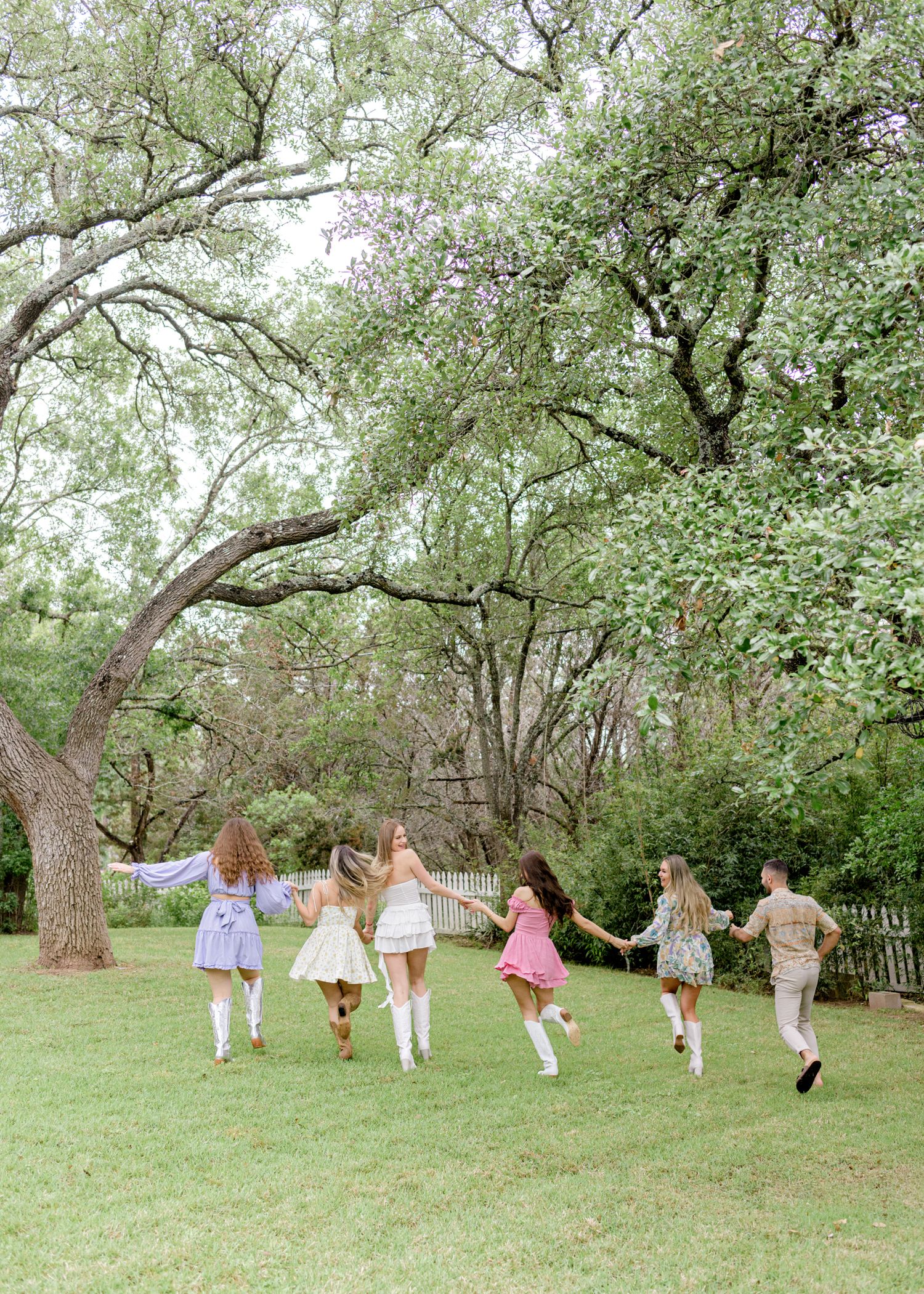 Group running through blooming spring trees on grassy lawn.