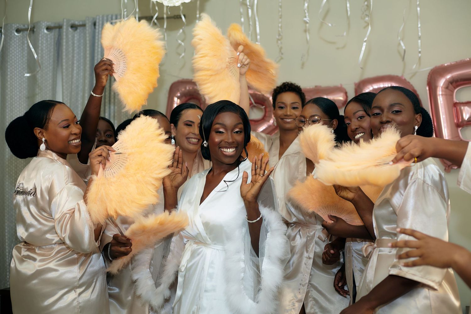 Group celebrating joyfully in white attire with raised arms and excited expressions.