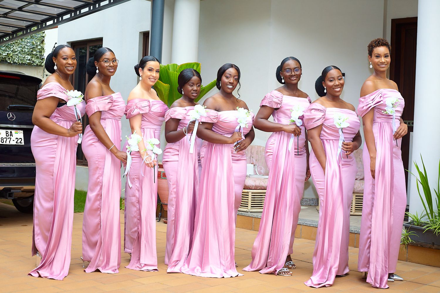 Bridesmaids in matching pink floor-length dresses lined up for a wedding photo.
