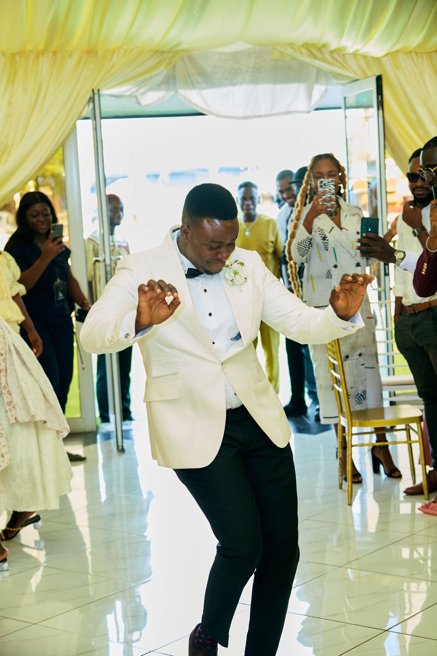 Wedding guests dancing in formal white attire at elegant reception venue.