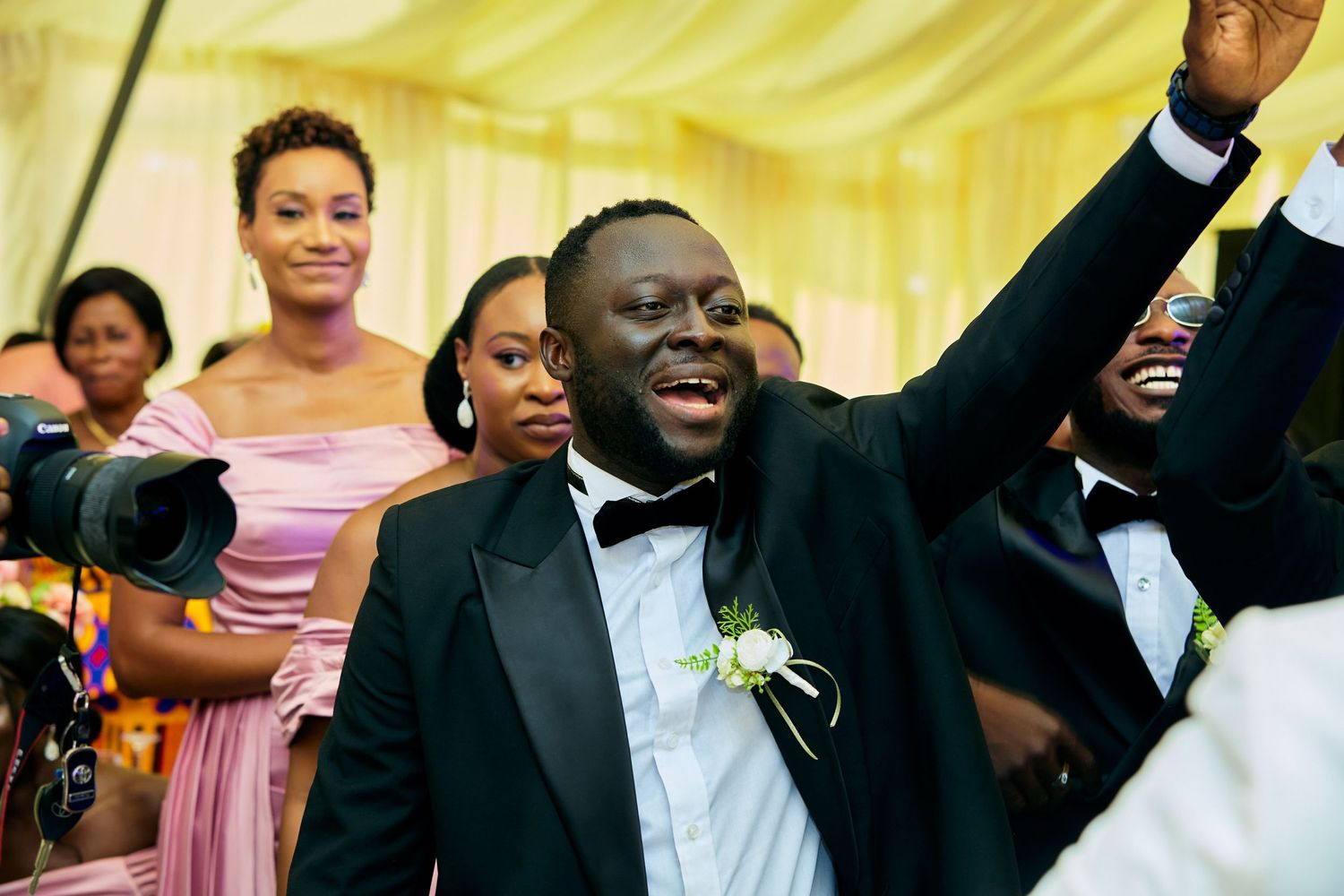 Wedding celebration scene with formal attire and festive yellow backdrop.