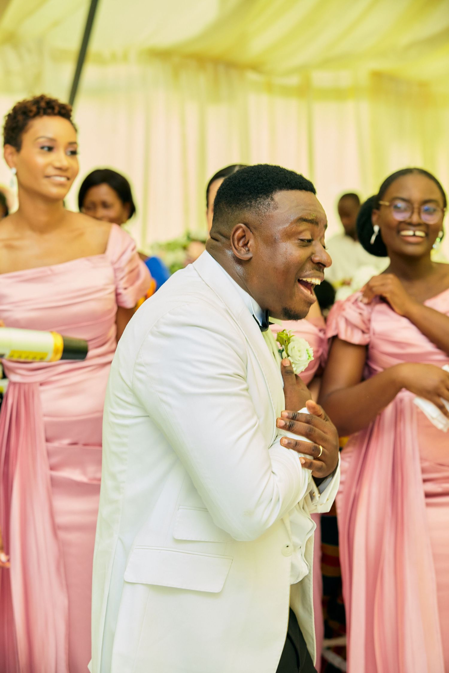 Wedding party members share joyful laughter during reception celebration.