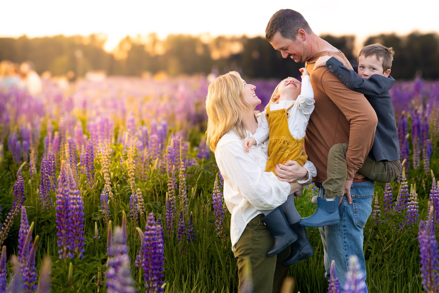 A family pose for photos in a field of endless purple lupine in Puyallup, Washington.