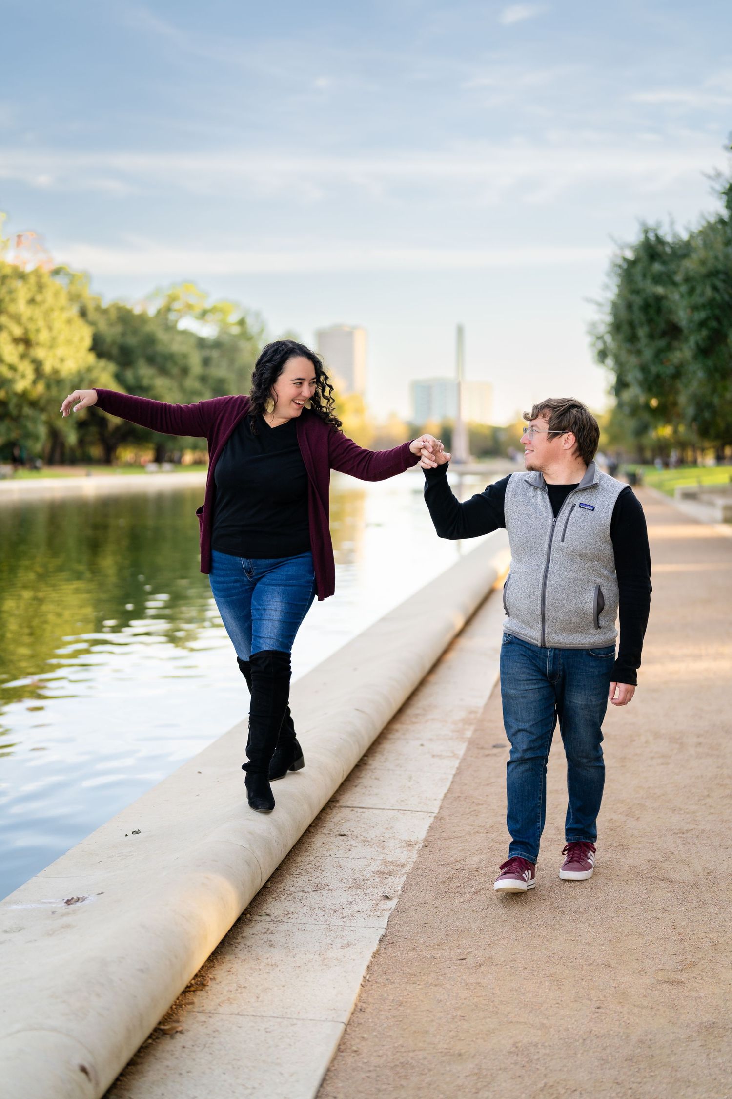 A playful moment captured along a waterfront path with city monuments visible in the background.