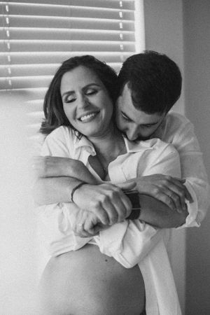 A black and white intimate maternity photo with a couple embracing.