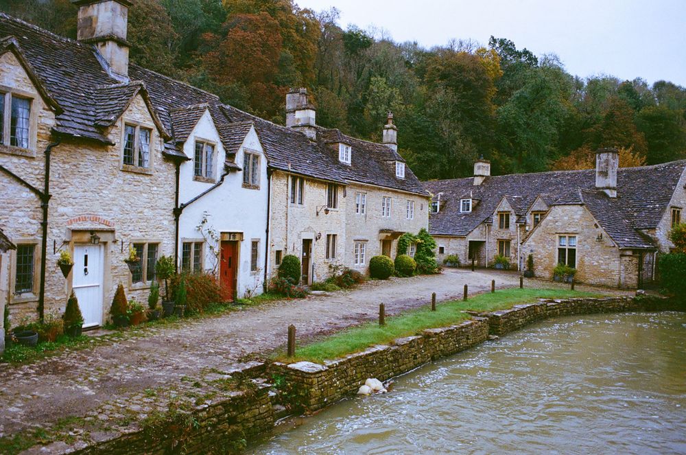 Charming row of traditional Cotswold stone cottages along a village street.