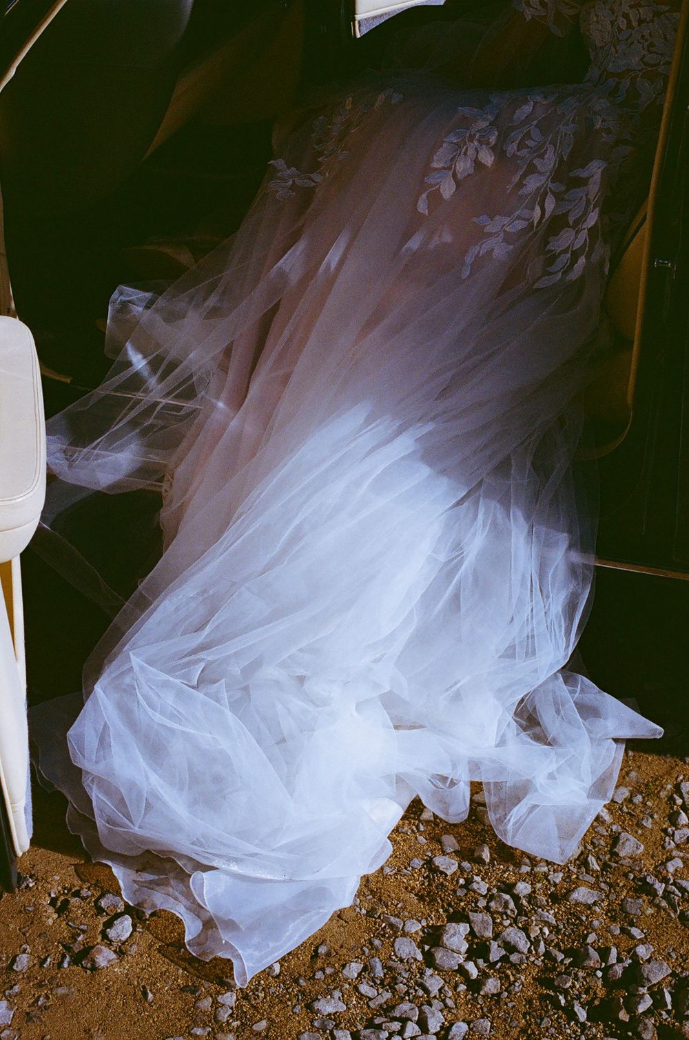 Close-up of white tulle wedding dress fabric against a dark background.