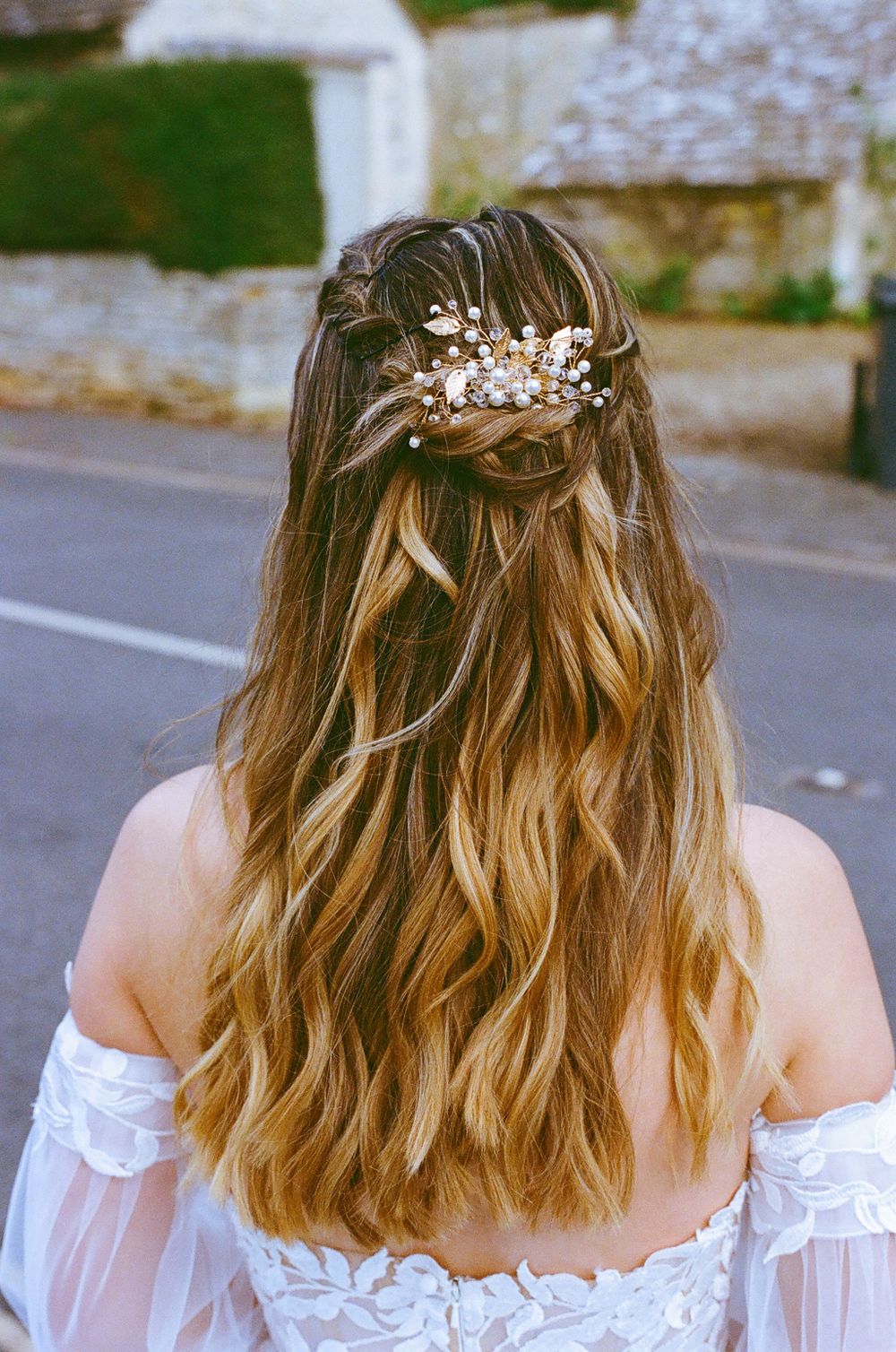 Bridal hairstyle with delicate floral accessories and braided details shown from behind.