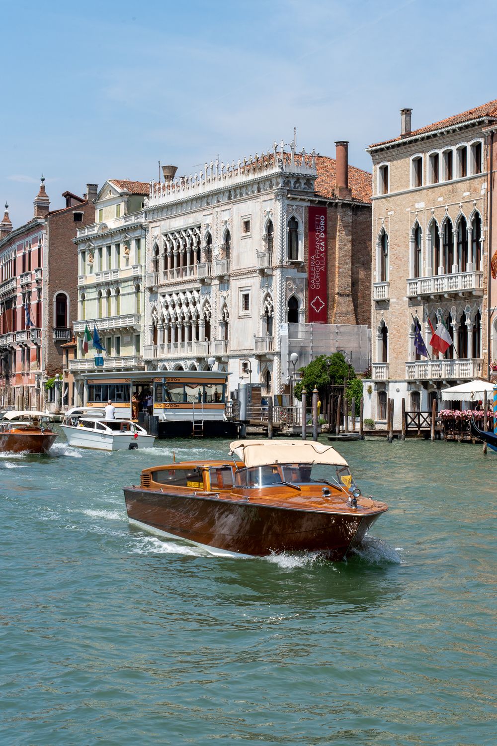 Traditional wooden water taxi cruises past ornate Venetian Gothic palaces along the Grand Canal.