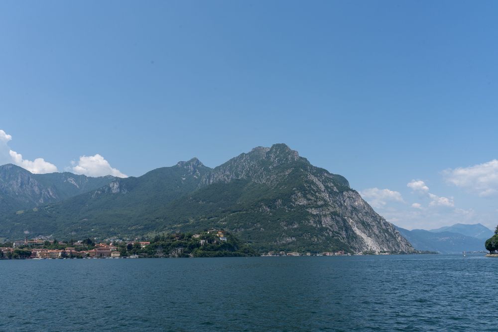 Scenic mountain lake view with rugged peaks and coastal settlement along turquoise waters.
