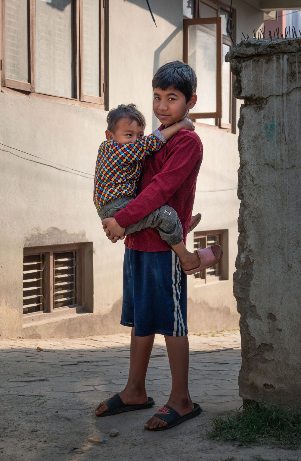 Children standing in courtyard against wall with traditional clothing in Nepal.