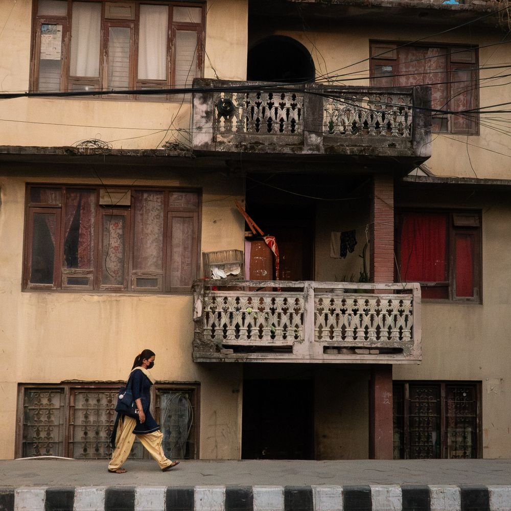 Three-story traditional building with wooden balconies and windows in an urban setting.