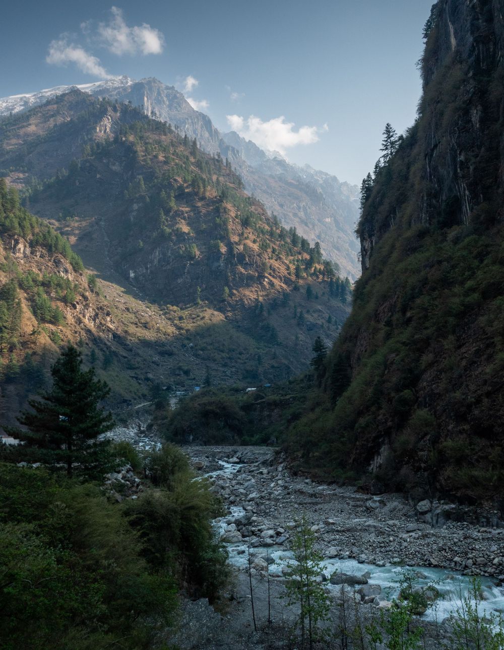A scenic mountain valley with a winding river and steep cliffs in the Himalayas.