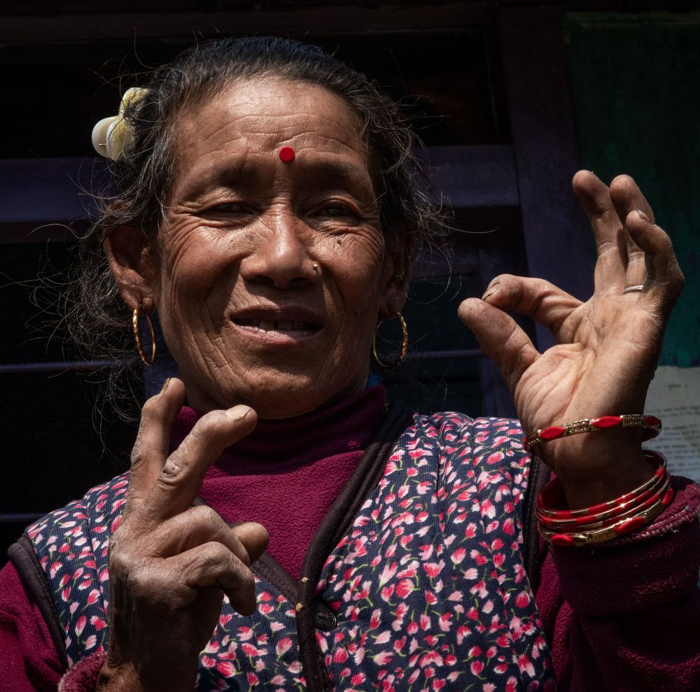 Local woman in traditional Nepali attire showing peace sign gesture.