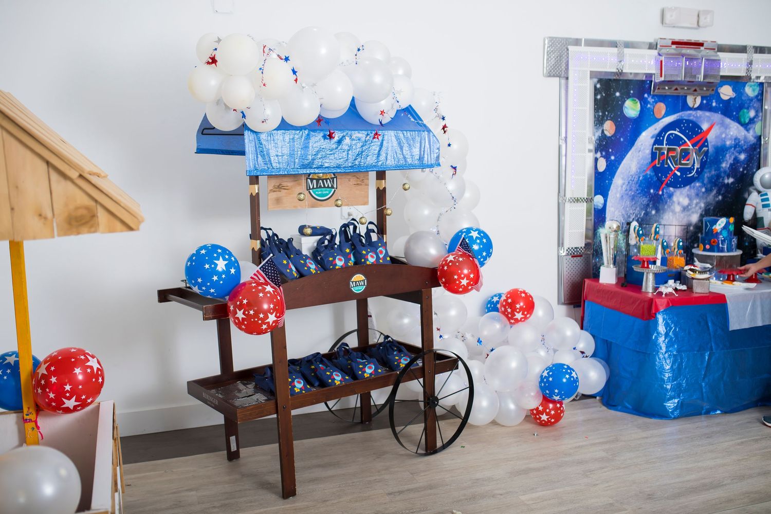 Blue and red balloon decorated dessert cart with party supplies.