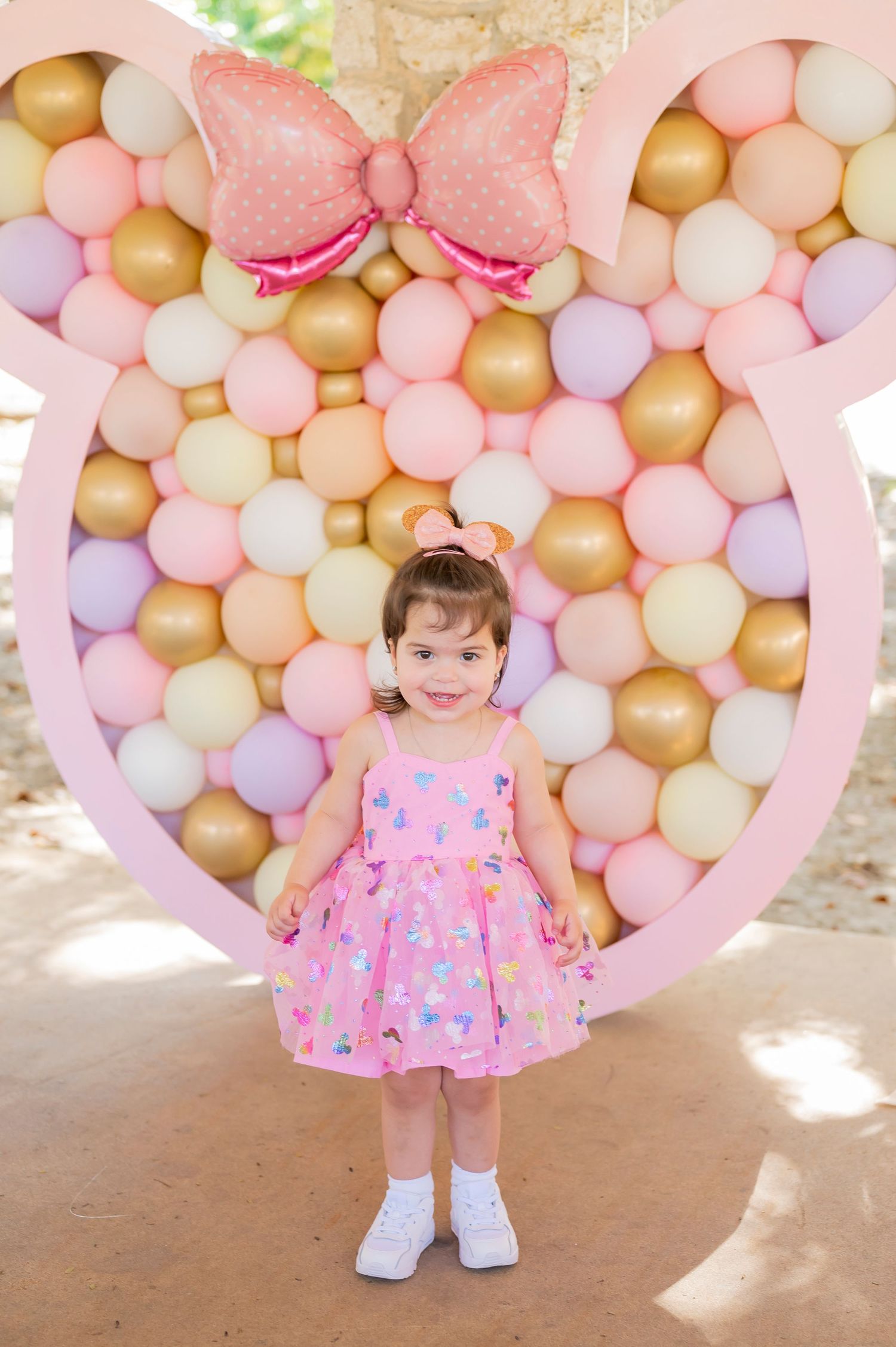 Festive balloon wall with pink bow design creates perfect photo backdrop.