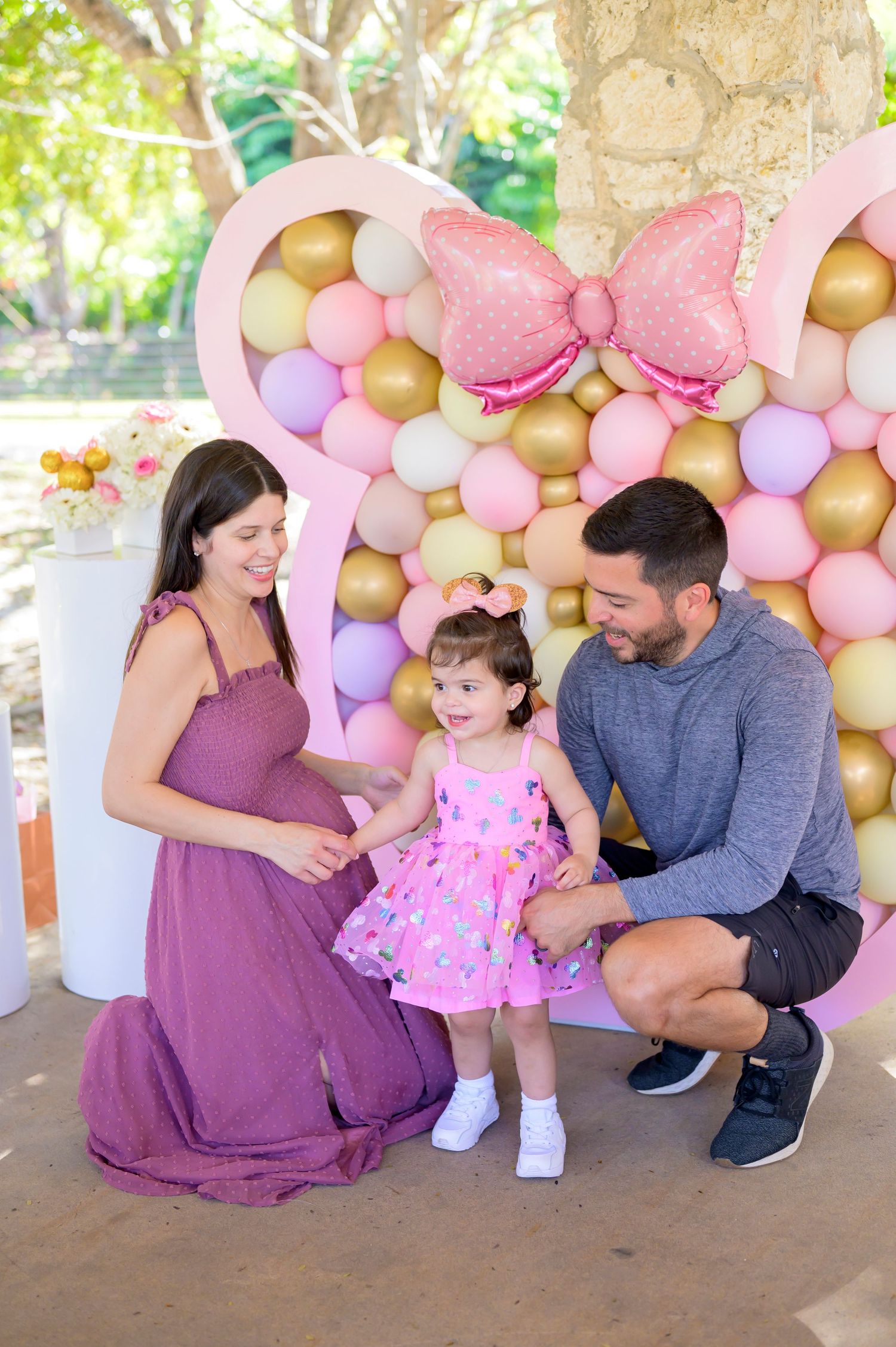 Sweet family moment captured against pink and gold balloon decoration.