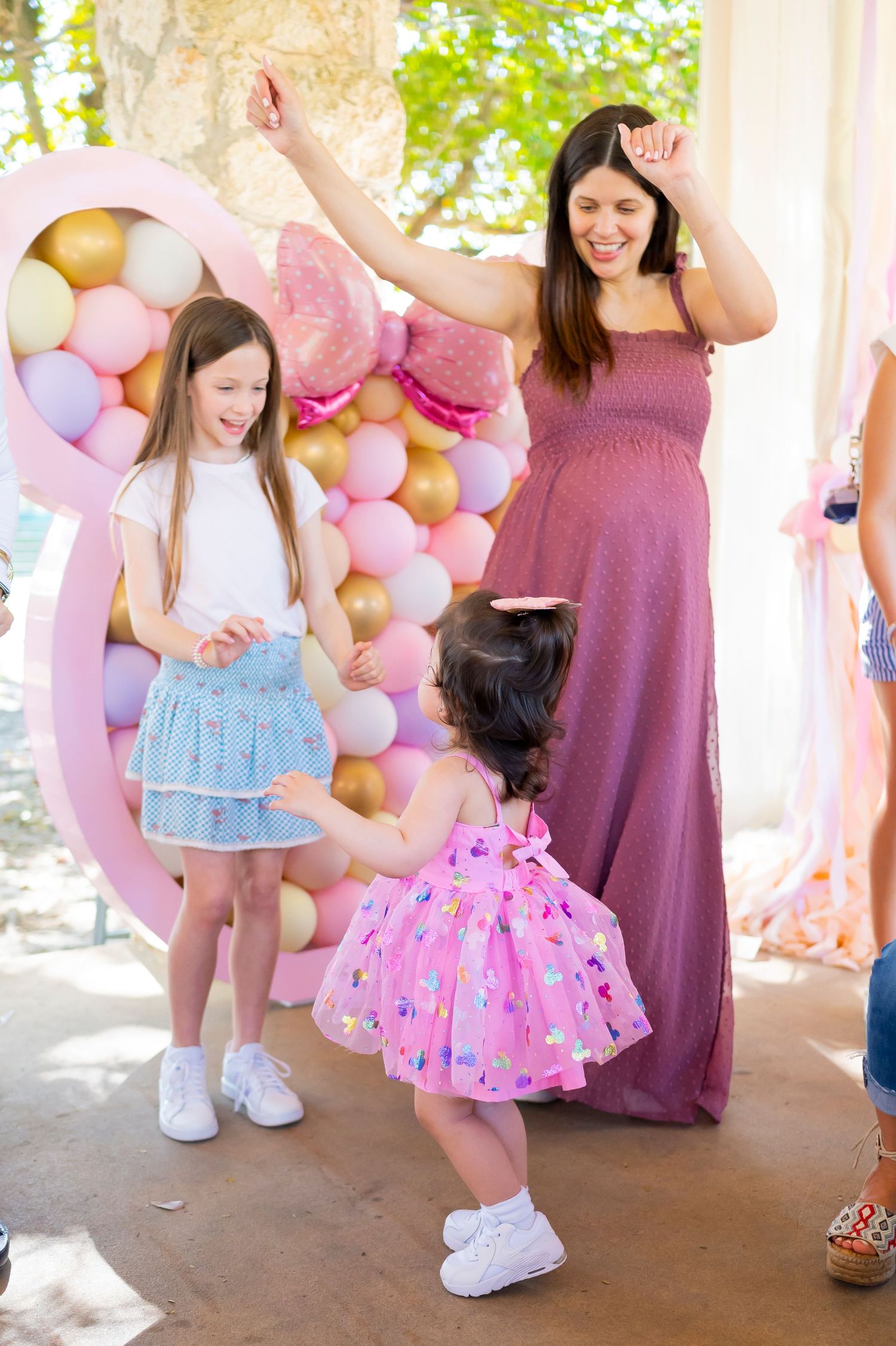 Dancing and celebration at a party decorated with pink and gold balloons.