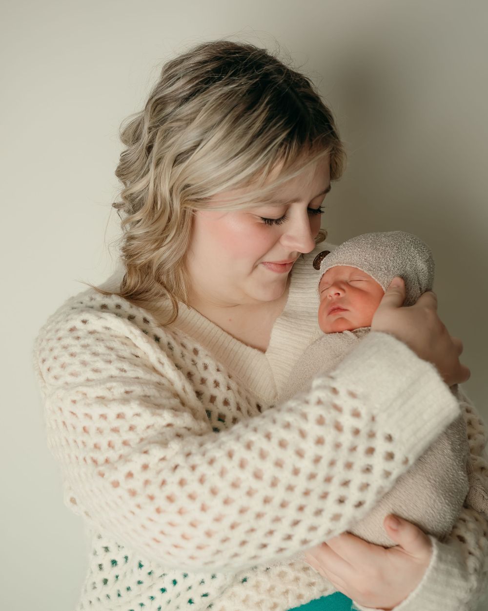 Intimate portrait of nurturing moment with sleeping newborn in soft natural light.
