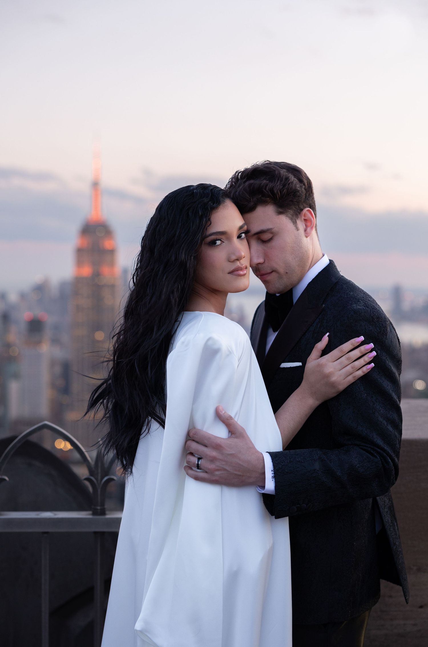 Romantic rooftop wedding portrait with Empire State Building visible in background at sunset.