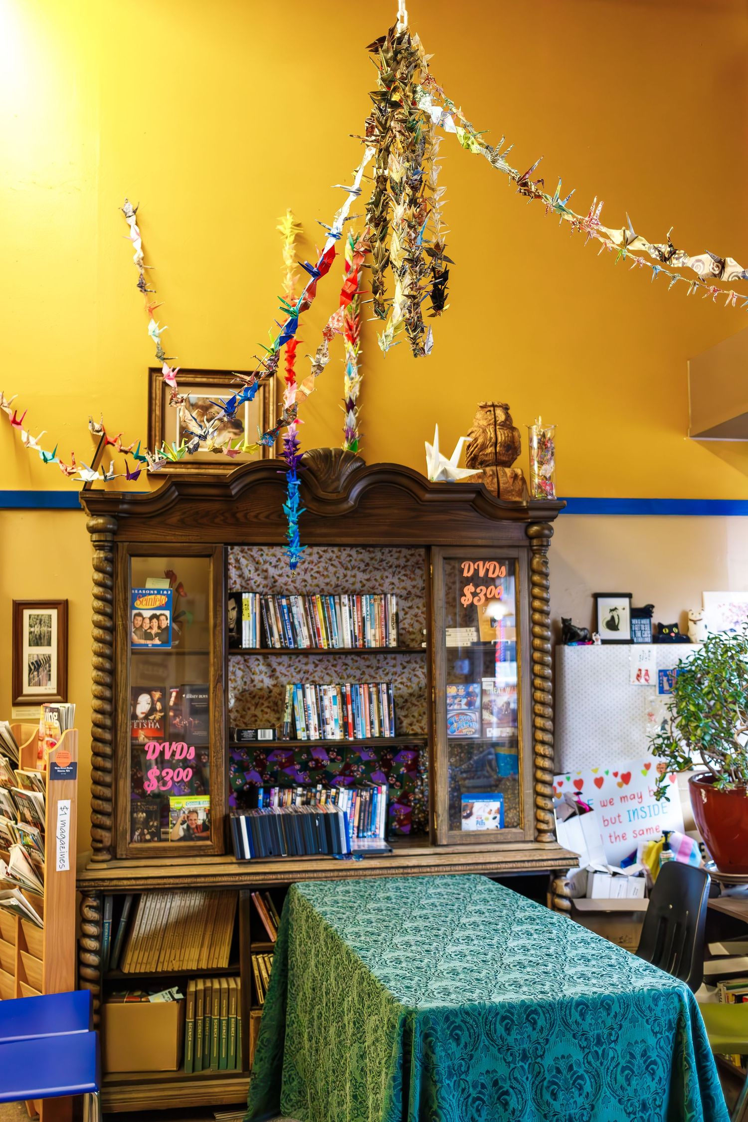 Decorated bookshelf with hanging lights and a green tablecloth in a cozy reading nook.