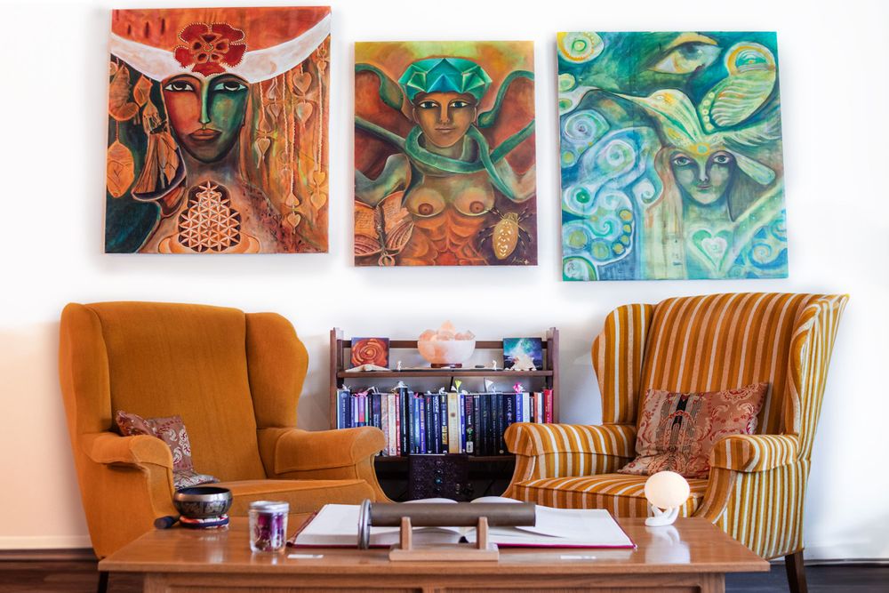 Modern living room with orange armchair, striped furniture, and vibrant wall art.