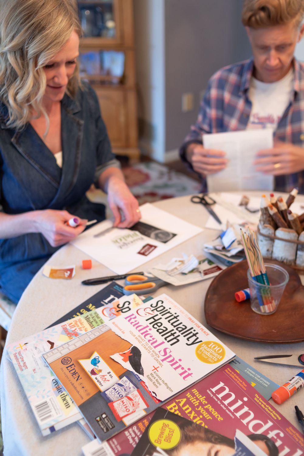 Creative workspace with books and crafting materials spread across white table.