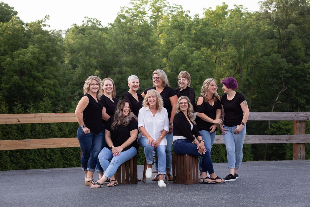 Group photo of people wearing black outfits posed on wooden deck outdoors.