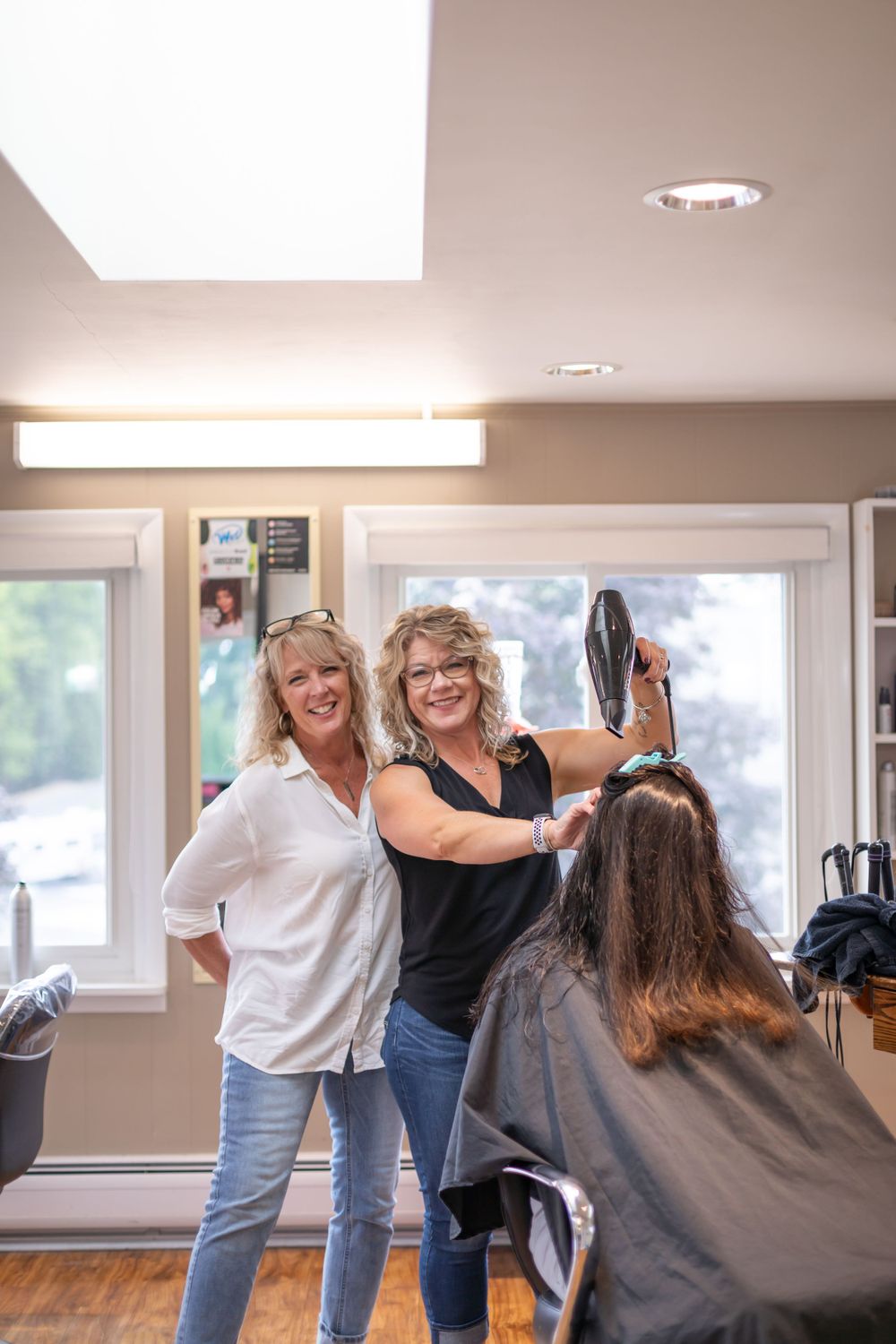 Bright, modern salon interior with stylists working on client's hair.