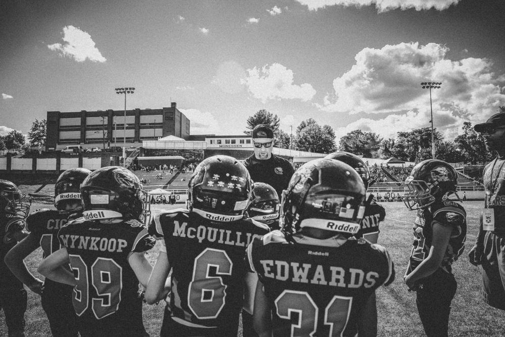 Black and white photo of football players from behind showing jersey numbers and names.
