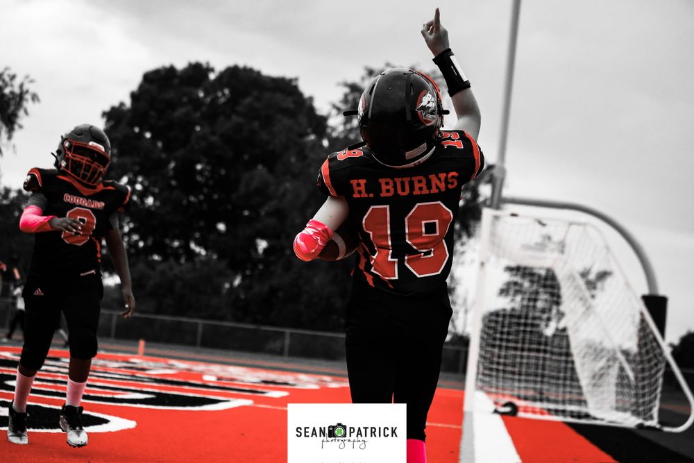 Selective color photo of a football player in a red jersey celebrating on the field.