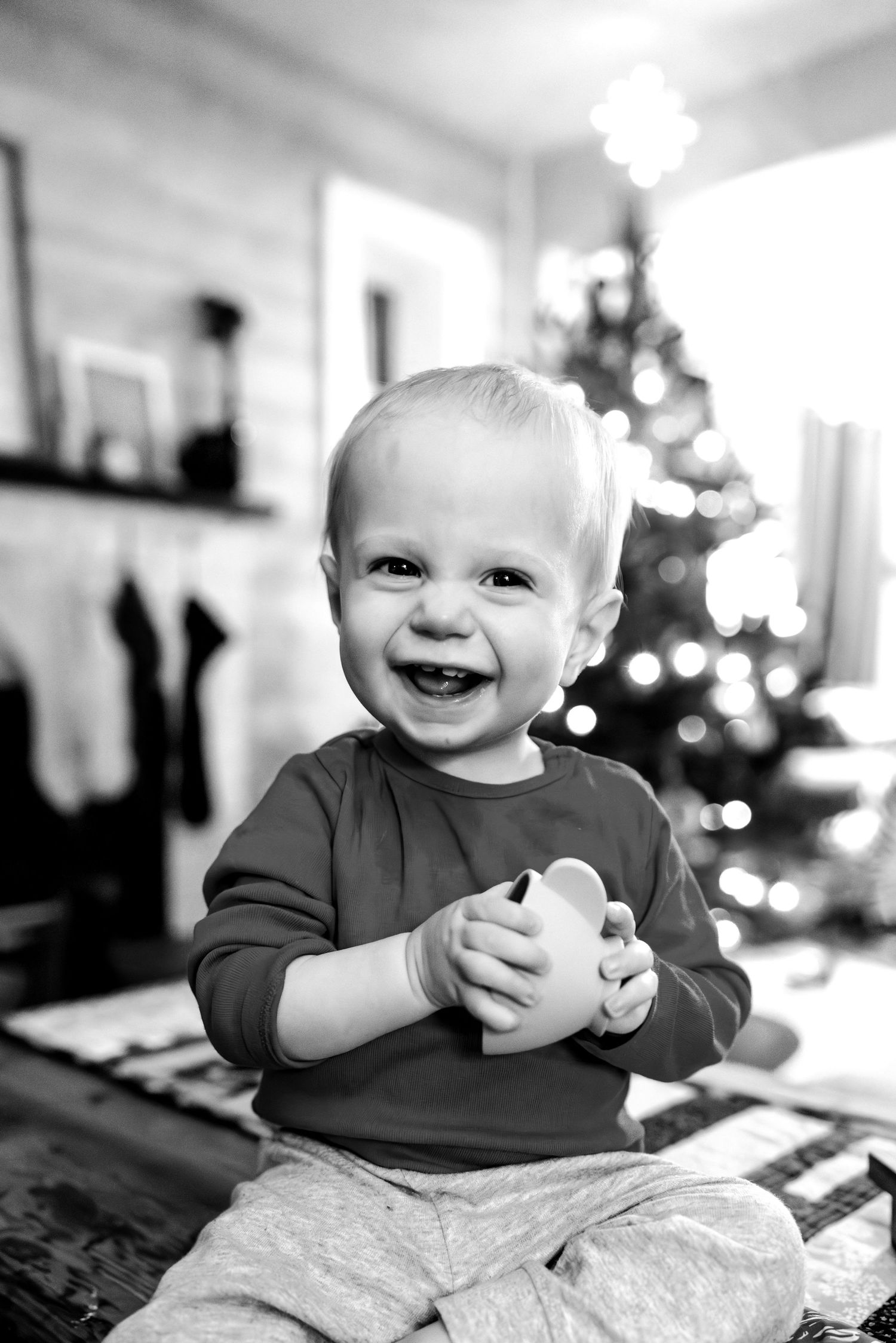 Black and white photos of a baby laughing and playing on a blanket.