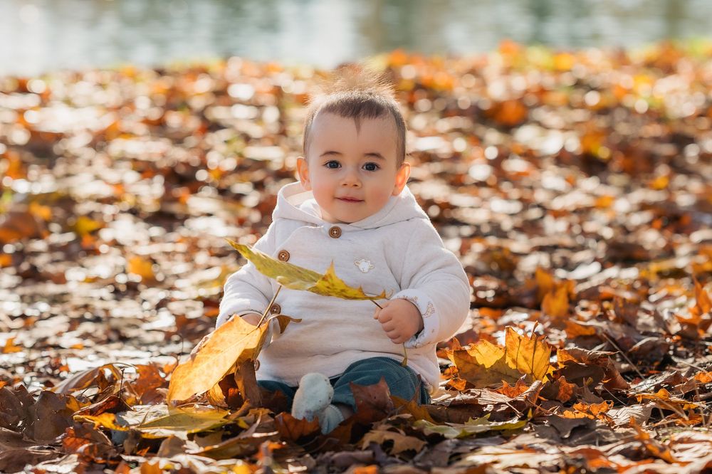 Bébé jouant dans les feuilles d'automne