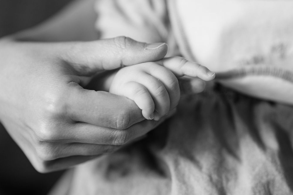 Petite main de bébé tenue par celle de sa maman