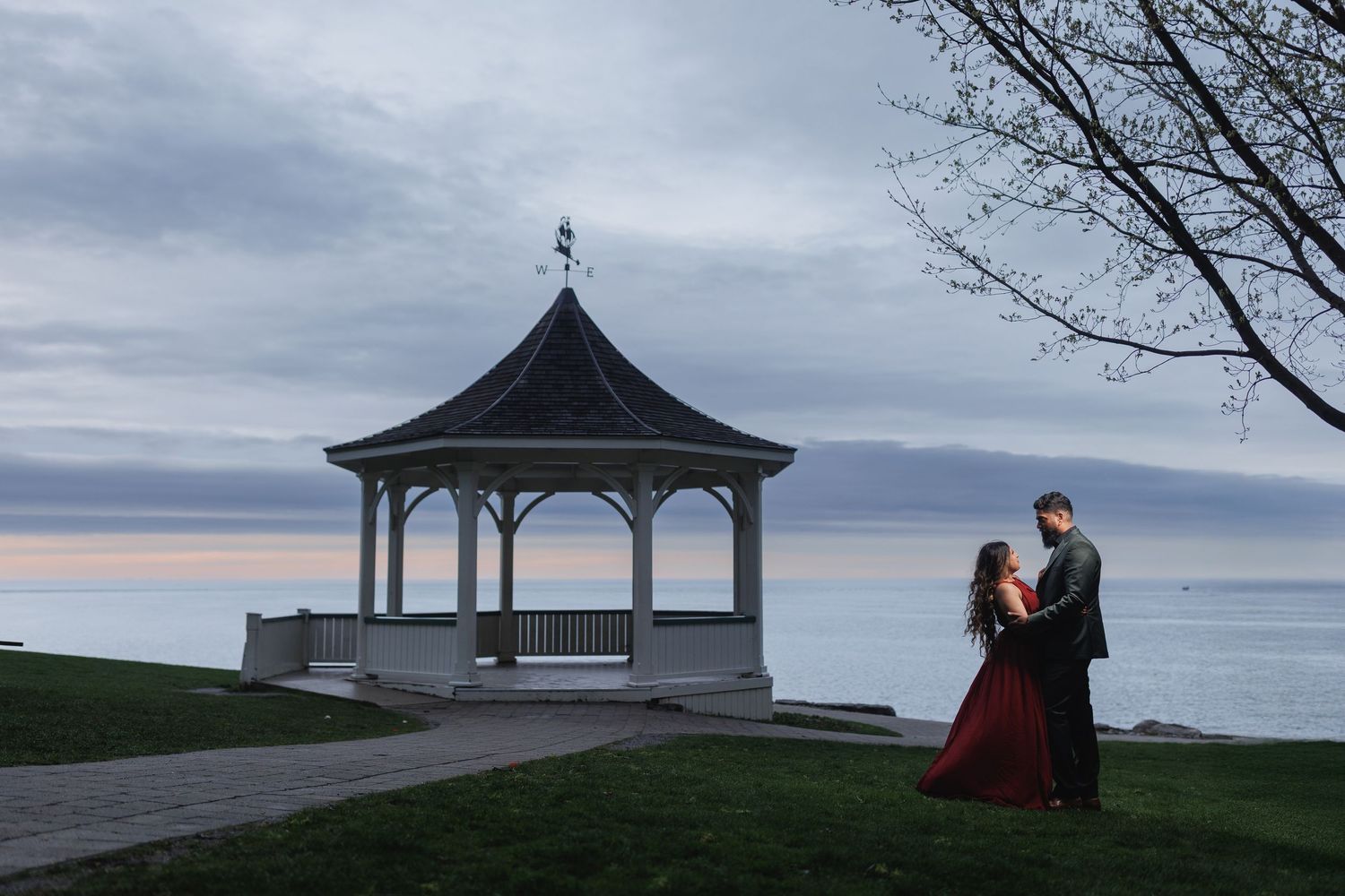 Romantic silhouette of couple by gazebo overlooking ocean at sunset.