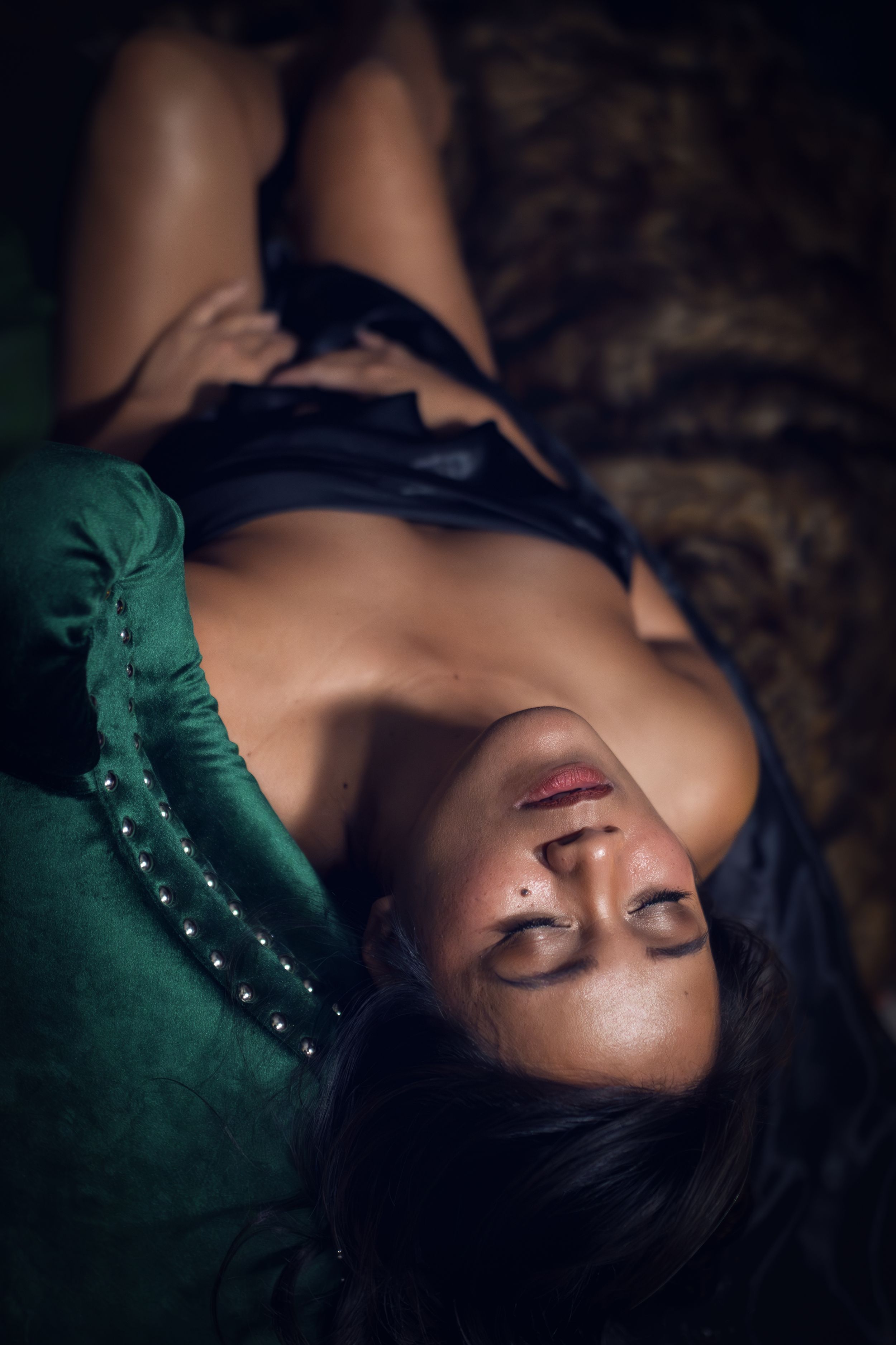 Boudoir photo showing someone lying down wearing a green top against a dark background.