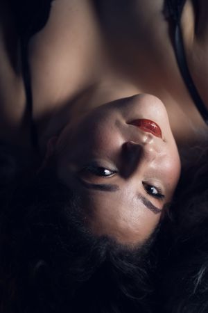 A dramatic artistic portrait taken from above showing red lipstick and dark hair against a shadowy background in Fort Worth, TX.