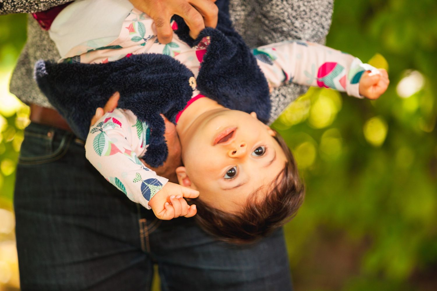 Bébé la tête en bas dans les bras de son papa