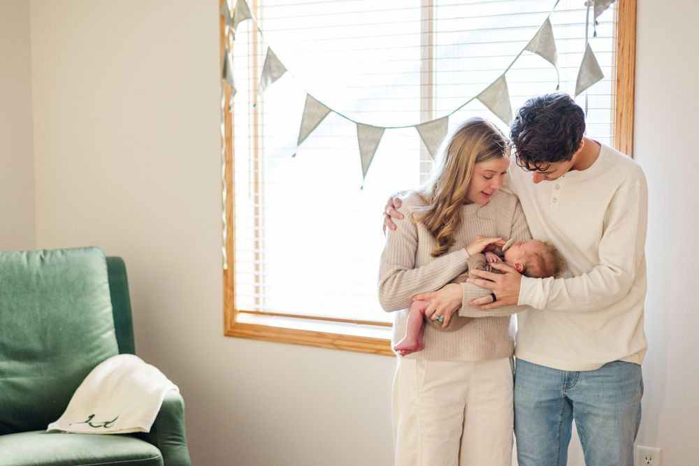 A couple in cream sweaters share an intimate moment by a window with decorative bunting.