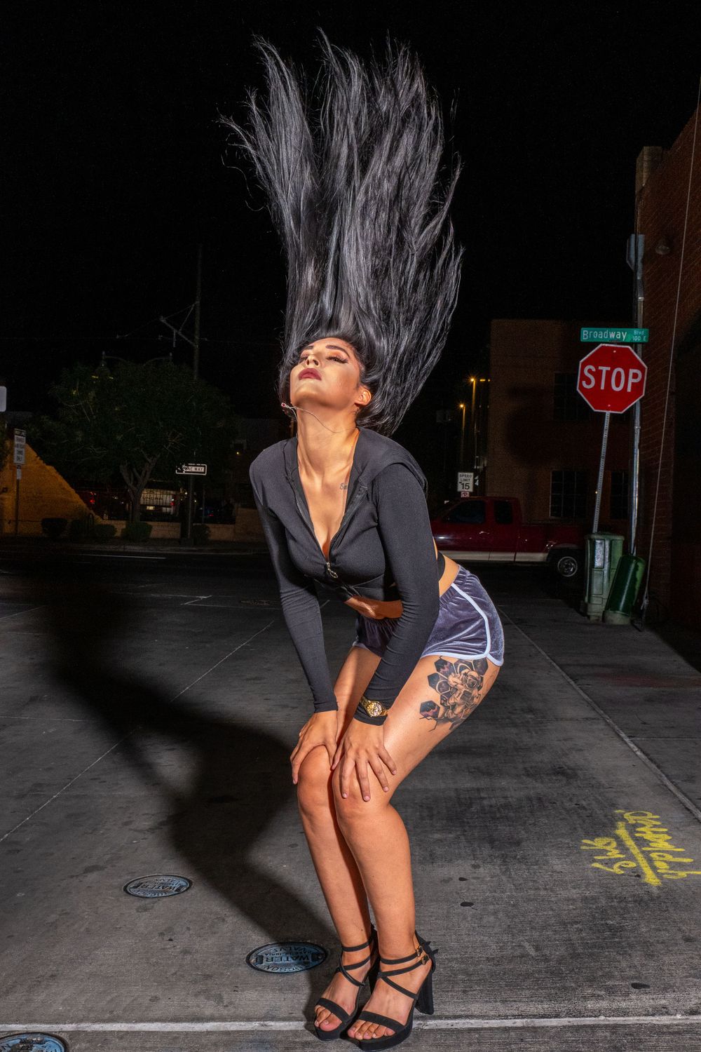 Dynamic street photography with flowing hair movement against urban nighttime setting.