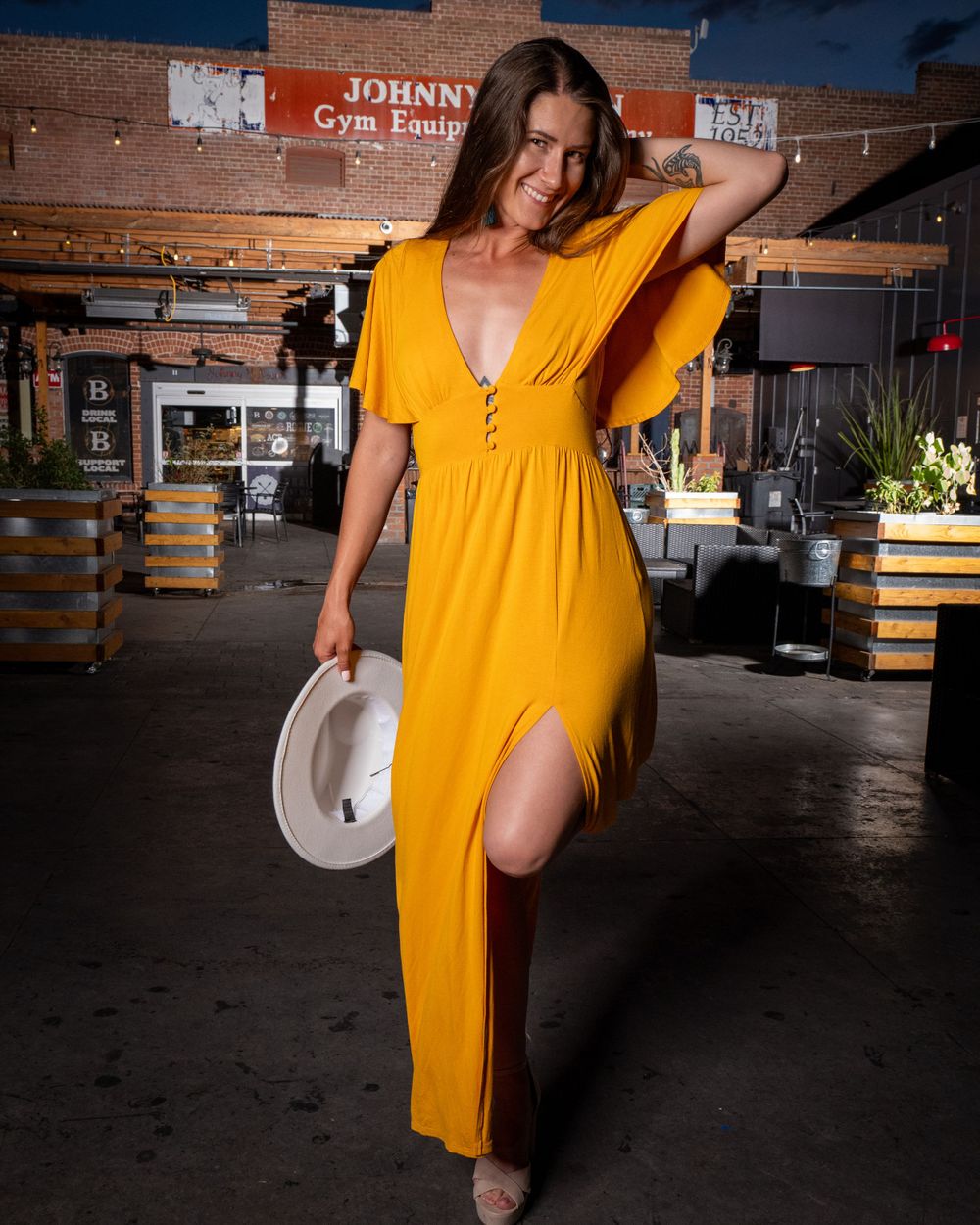 Sunny yellow maxi dress with slit photographed in industrial space with wooden barrels.