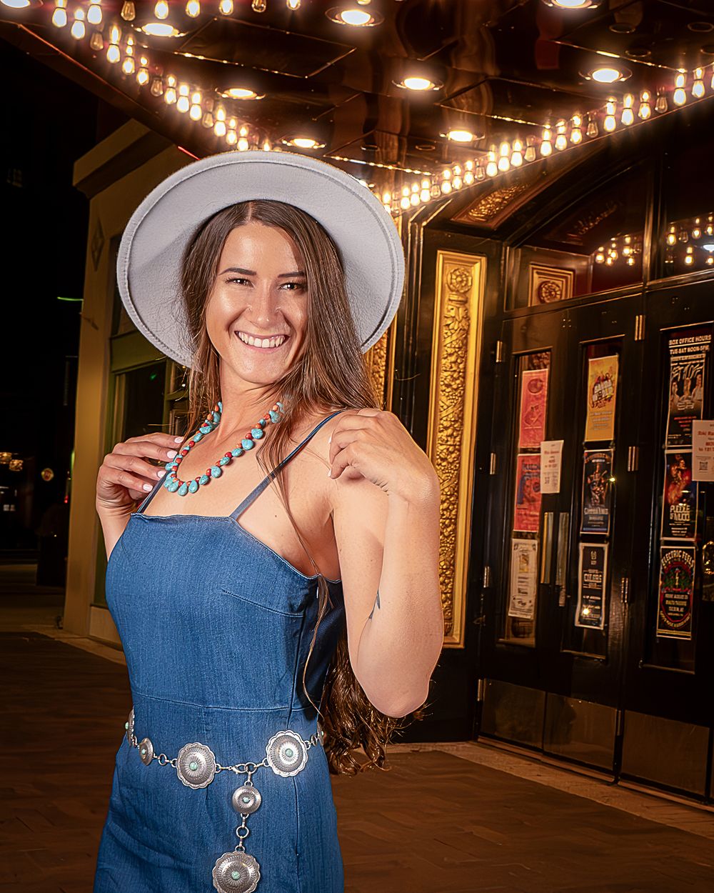 Denim outfit with turquoise jewelry captured under vintage theater lighting.
