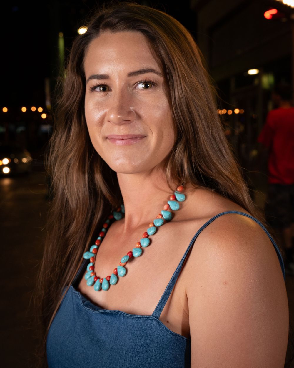 Turquoise necklace complements denim outfit in nighttime portrait.