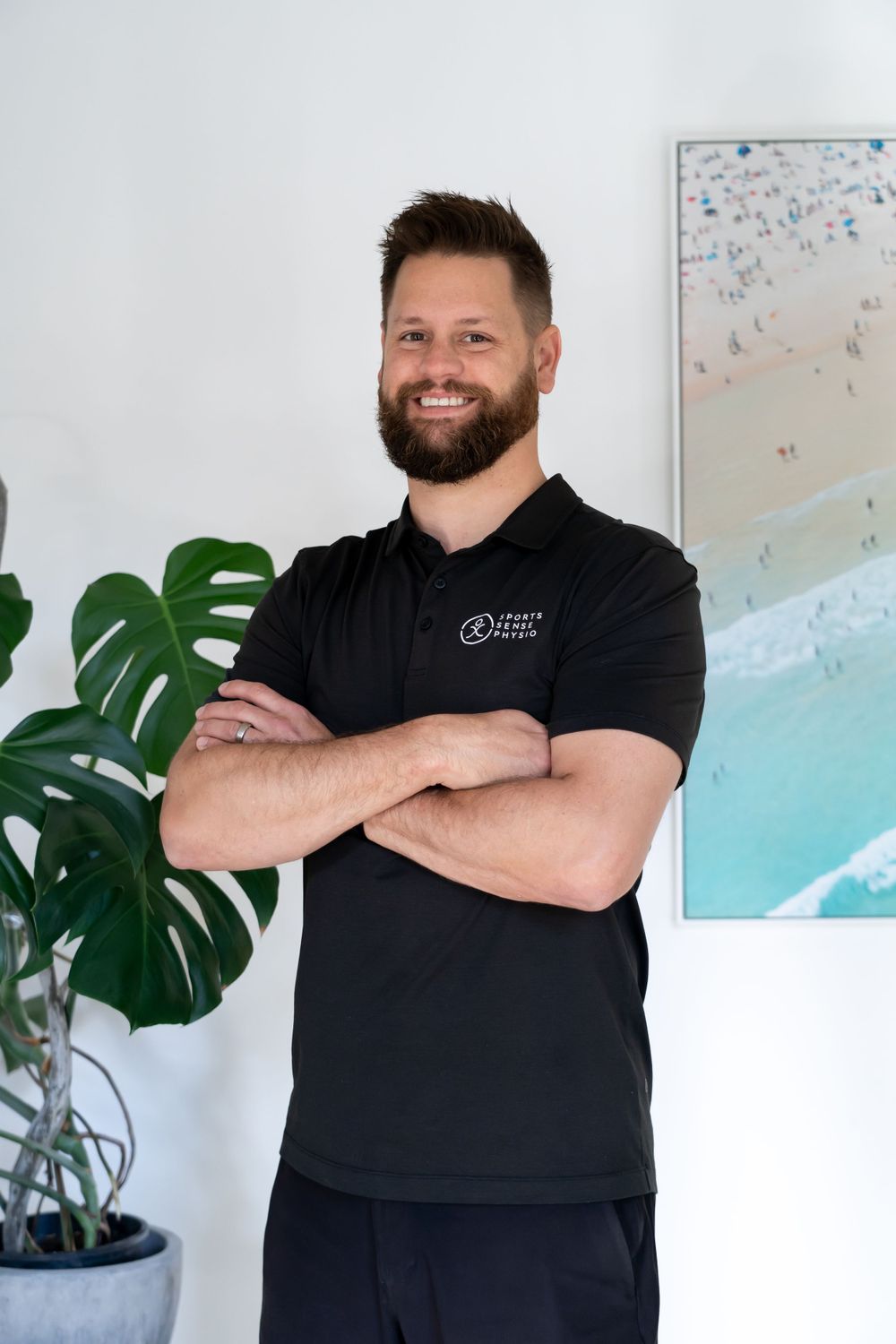 Professional healthcare worker in black polo shirt poses in modern clinic setting.
