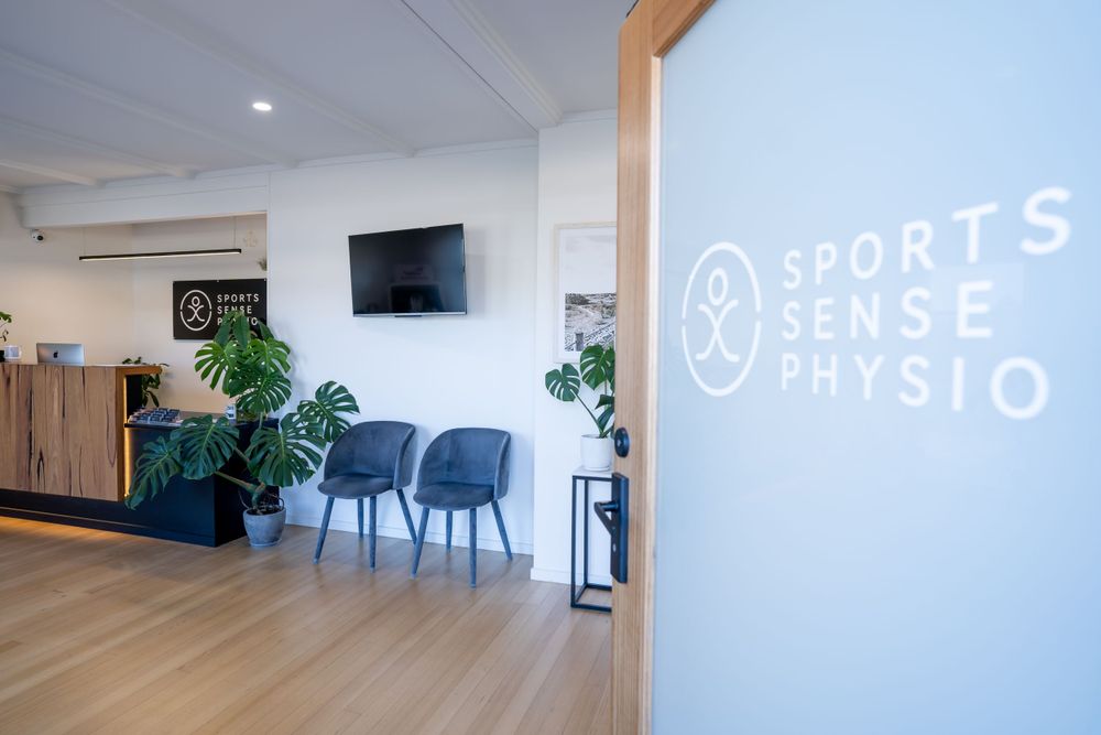 Modern physiotherapy clinic waiting area with Sports Sense Physio branding on wall.