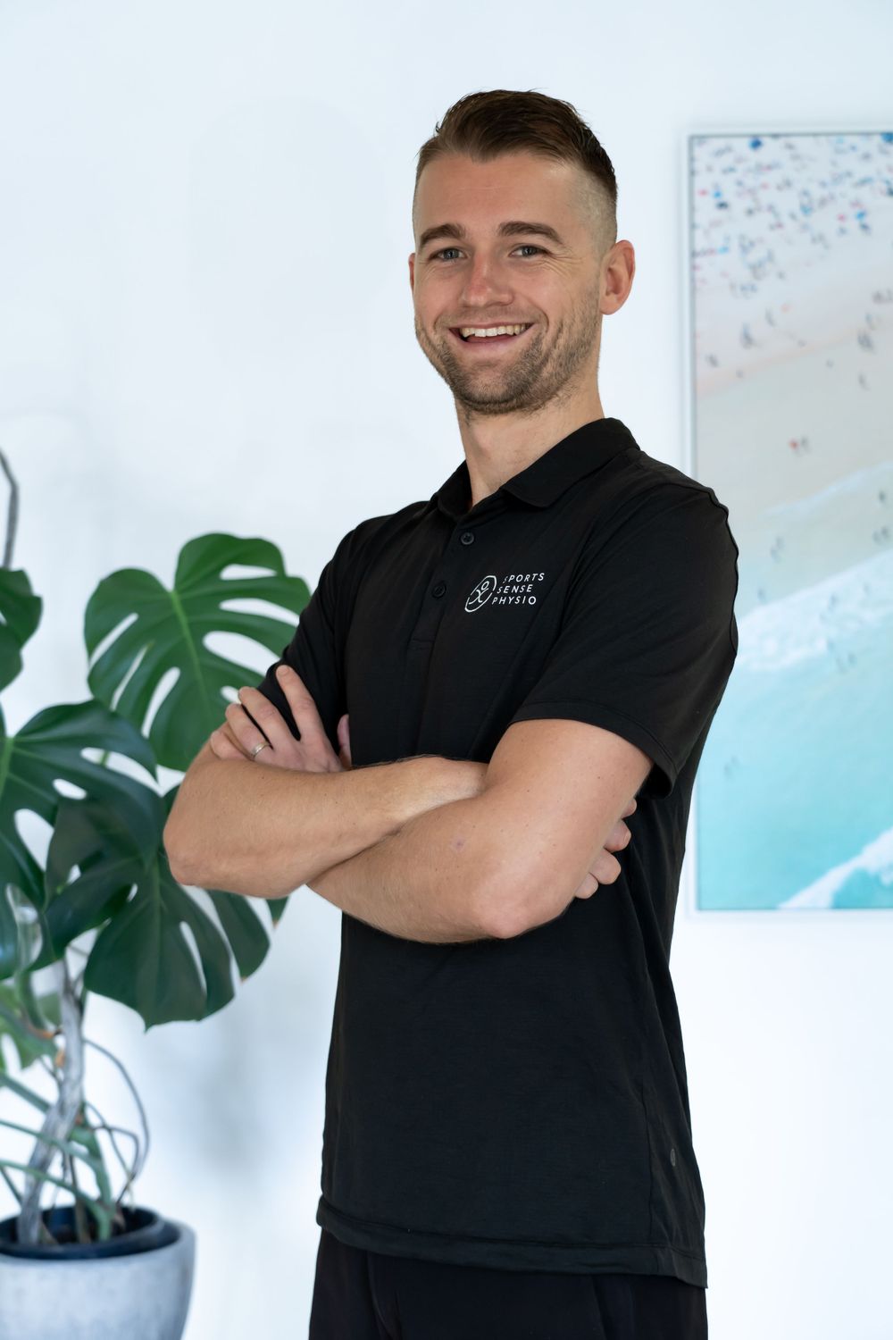 Medical professional in black polo smiles confidently in modern clinic setting.