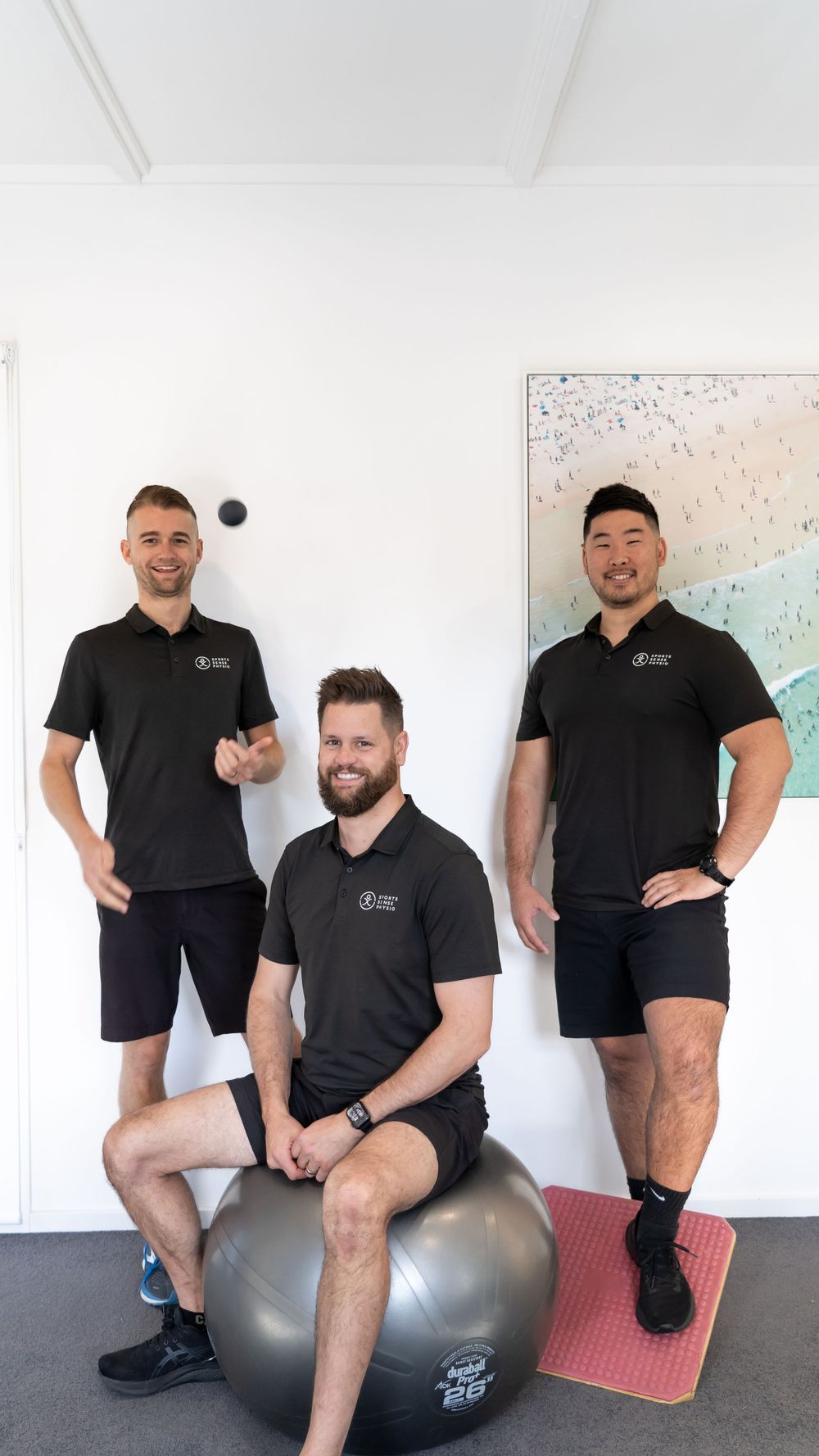 Sports physiotherapy team posing in modern clinic with exercise equipment.